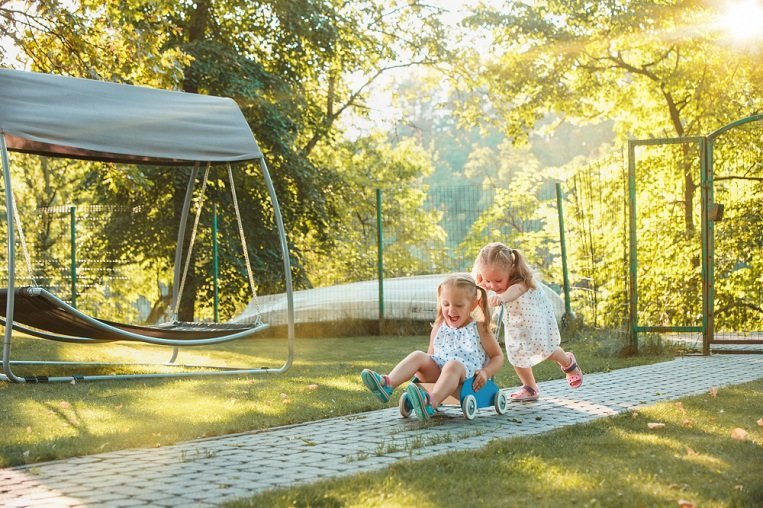 Hotel and serviced apartment tips for families traveling with children cute little blond girls riding toy car summer